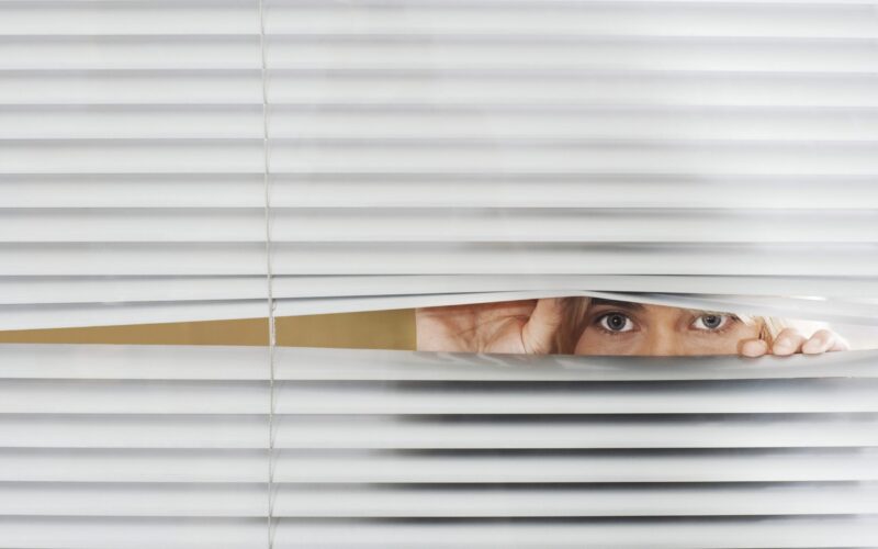 Woman Looking Through Venetian Blinds