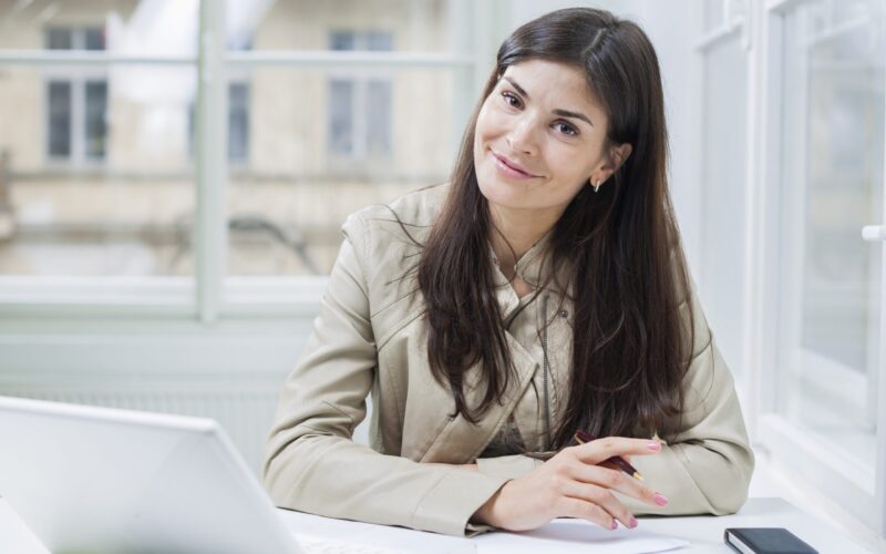 Portrait of confident businesswoman with laptop sitting at office desk